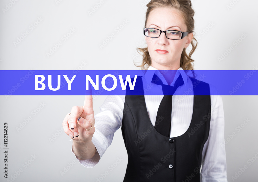 buy now written on a virtual screen. Internet technologies in business and tourism. woman in business suit and tie, presses a finger on a virtual screen buy now written on a virtual screen. Internet technologies in business and tourism. woman in business suit and tie, presses a finger on a virtual screen