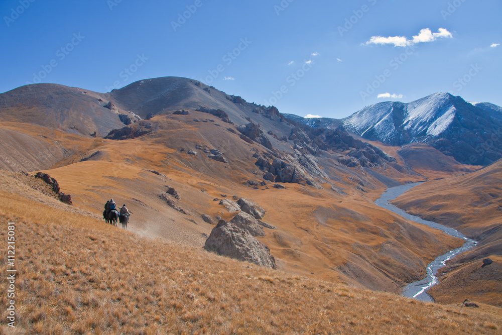 Fototapeta premium Three hunters on horses in mountains Tien-Shan
