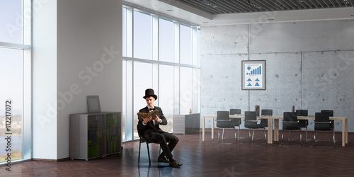 Businessman in cylinder reading book