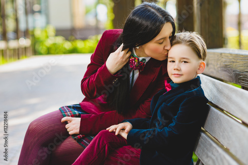 trendy mother kissing her stylish son outdoor