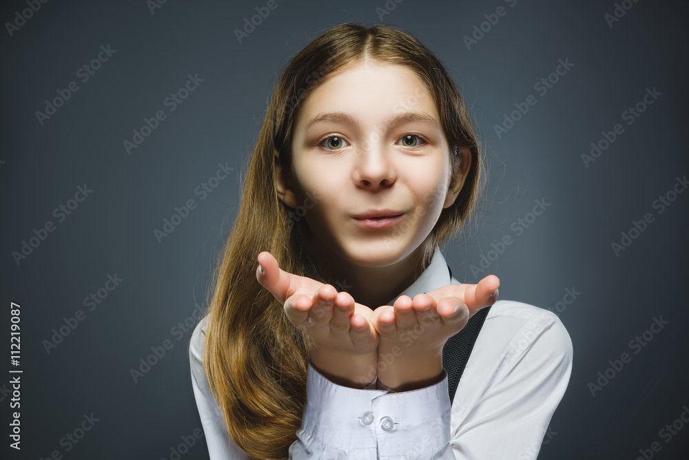 Beautiful Young girl Blowing A Kiss against grey background Beautiful Young girl Blowing A Kiss against grey background
