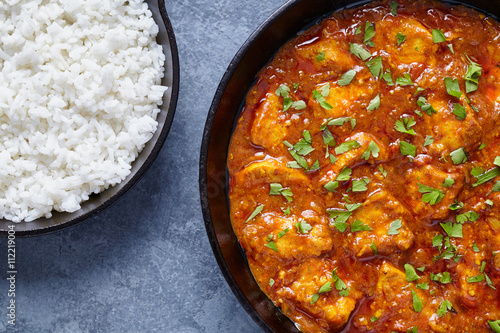 Chicken tikka masala national Indian spicy meat food with butter and rice in cast iron skillet