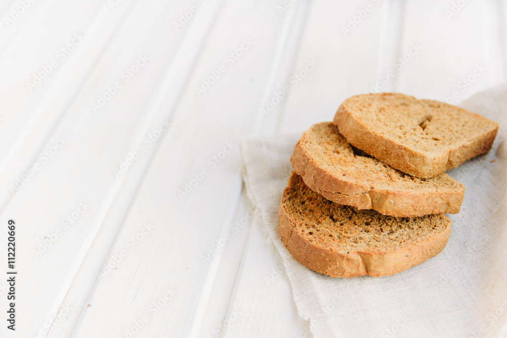 Slices of toast rye bread on napkin on white wooden boards with copyspace Slices of toast rye bread on napkin on white wooden boards with copyspace