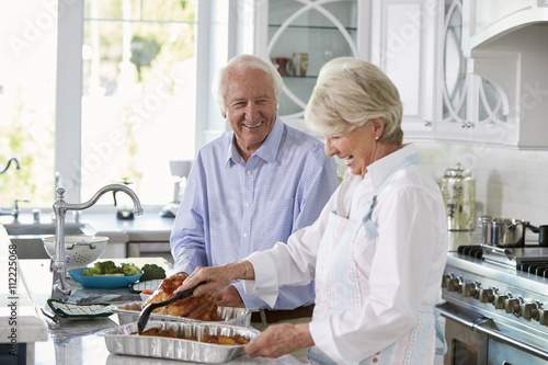 Bilde på lerret Senior Couple Make Roast Turkey Meal In Kitchen Together