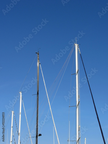 Sailboat masts in the marina against a blue summer sky