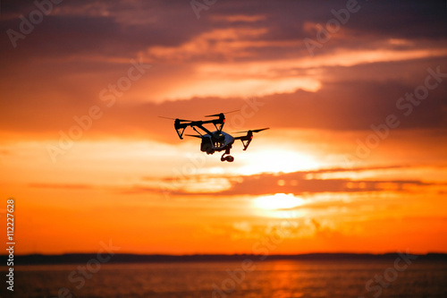 quadrocopter drone with remote control. Dark silhouette against colorfull sunset. Soft focus. Toned image