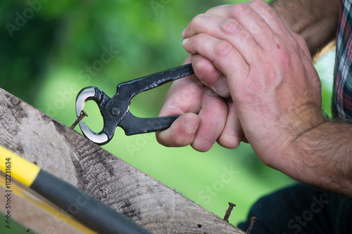 Pulling a carpenter tip on wood with pliers