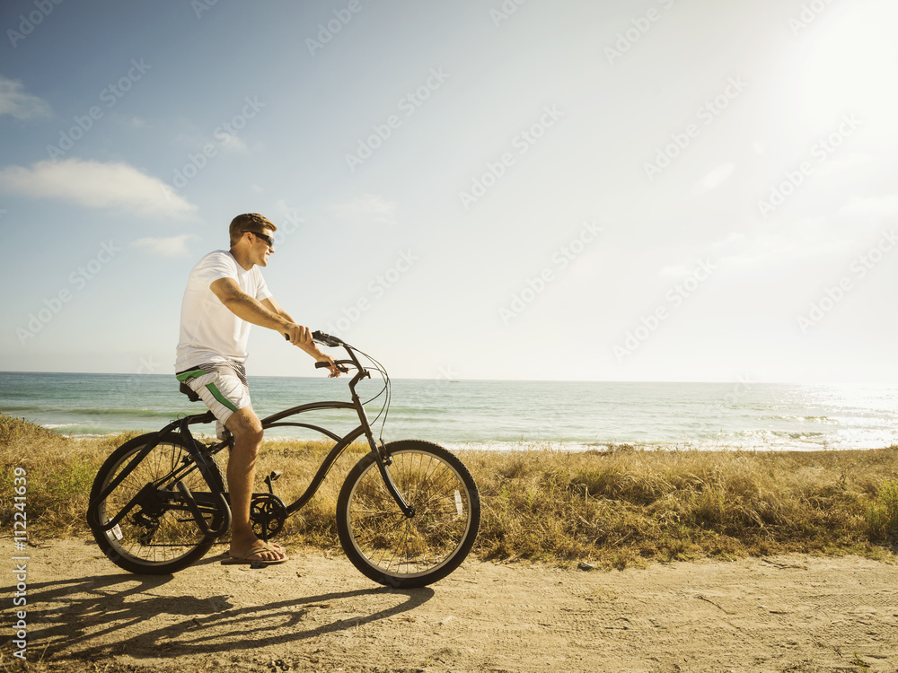 Caucasian man riding bicycle on beach Caucasian man riding bicycle on beach