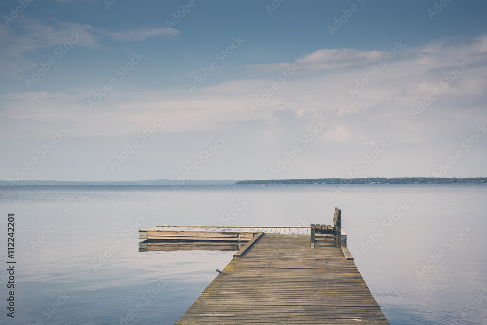Obraz premium Lake peer with wooden bench with beautiful sky clouds on sunset travel vacation. Print on canvas