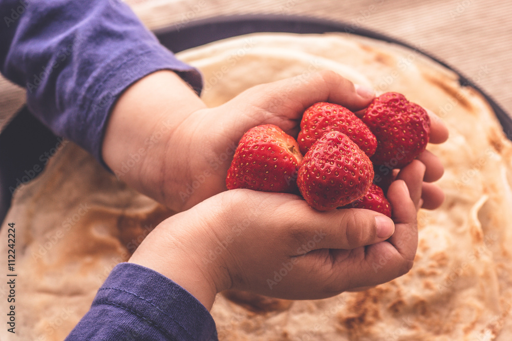 Fresh strawberries in child hands over plate with fresh french pancakes close up macro matte abstract idea of happiness and family Fresh strawberries in child hands over plate with fresh french pancakes close up macro matte abstract idea of happiness and family