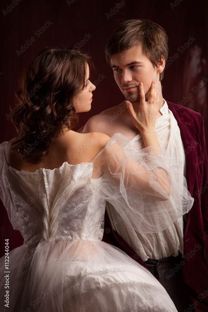 Beautiful man and woman dressed in medieval clothing stand in a room of the old abandoned castle.