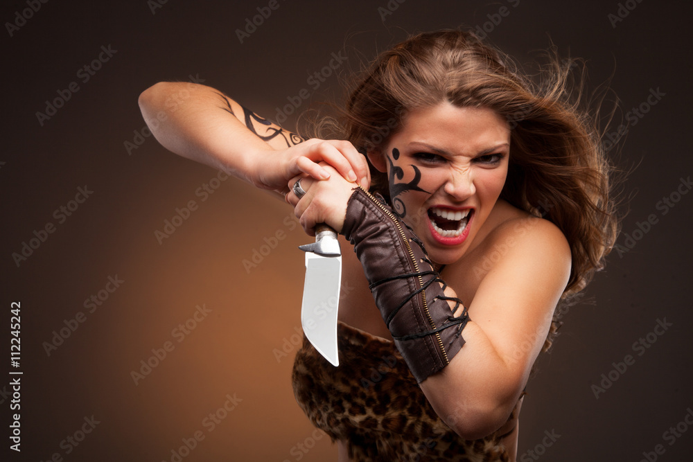 Obraz premium woman with sharp knife. amazon girl. tatooed face and hand