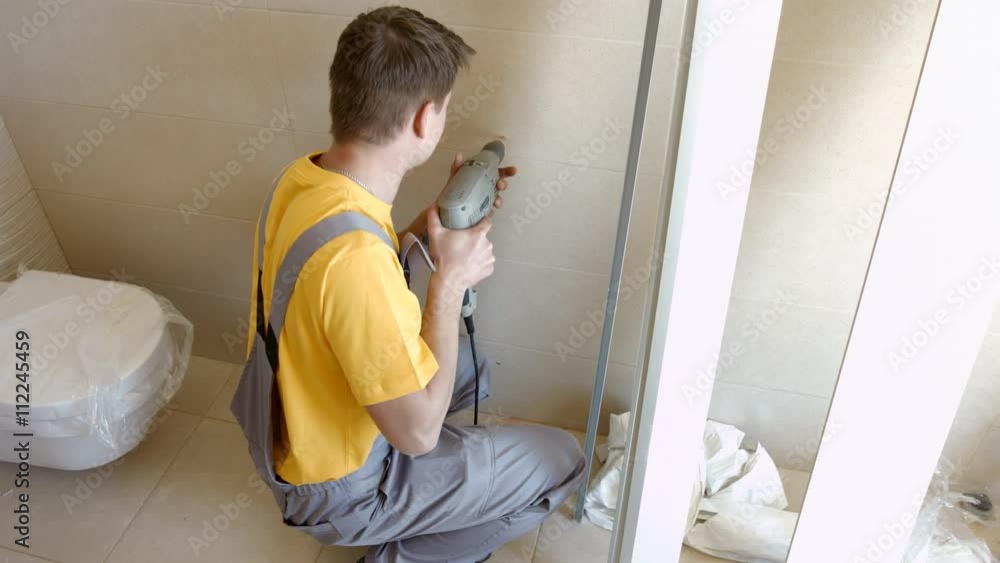 Young Man is Drilling Hole in the Wall With a Drill. Mounting Works