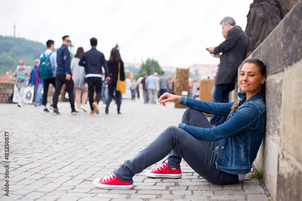 Fototapeta premium young woman sitting on the floor at charles bridge relaxing