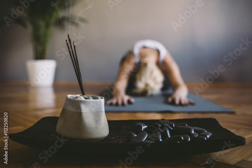 Woman practicing yoga in the gym with incense sticks in foreground photo