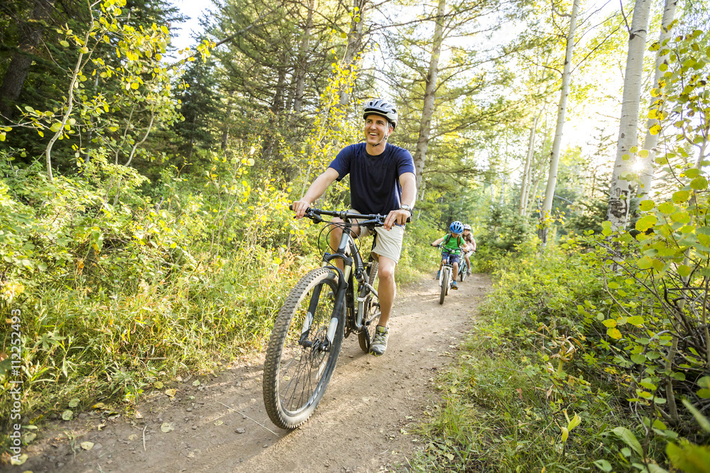 Caucasian father and children riding mountain bikes Caucasian father and children riding mountain bikes