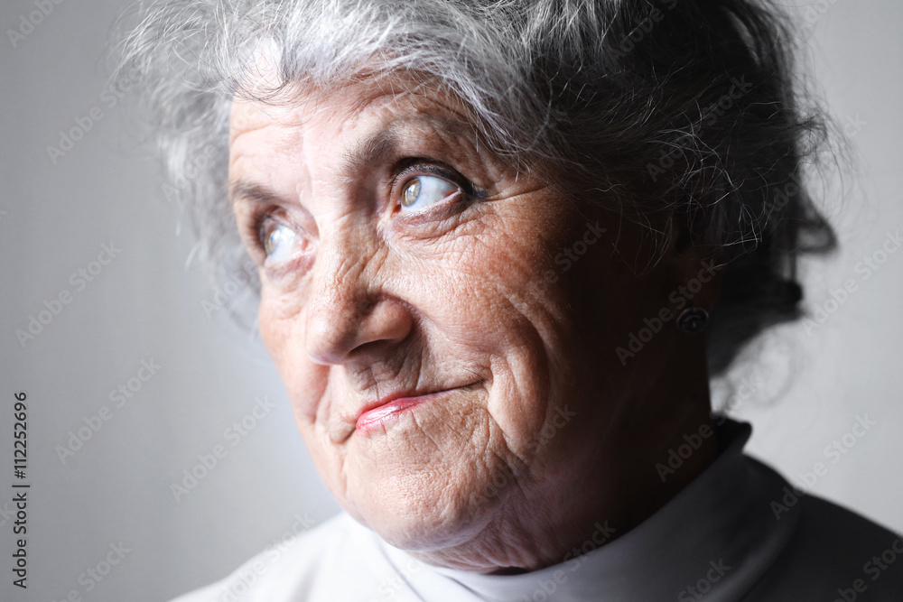 Looking old woman portrait on a gray background Looking old woman portrait on a gray background