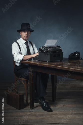 Vintage 1940 office worker behind desk with typewriter and telep photo
