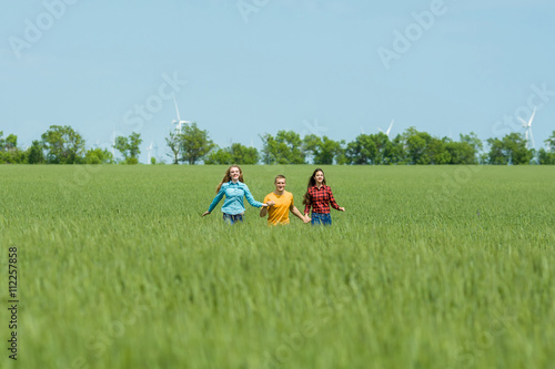 Young happy Friends running on green wheat field
