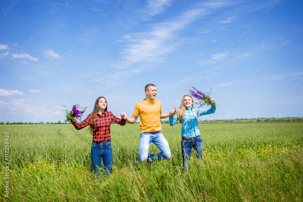 Young happy Friends running on green wheat field