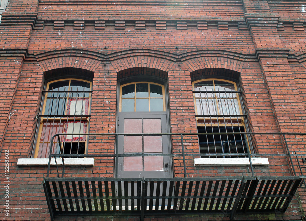 Obraz premium Fire Escape at a Door on the Upper Floor of a Red Brick Building