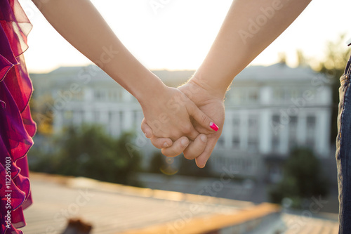 couple holding hands standing on the roof of the building, wide angle, lower point 