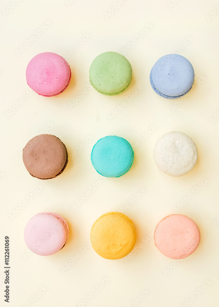 Sweet colorful French macaroon biscuits on pastel yellow background Sweet colorful French macaroon biscuits on pastel yellow background