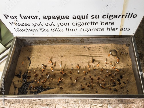 Big ashtray with cigarette fags on airport. photo