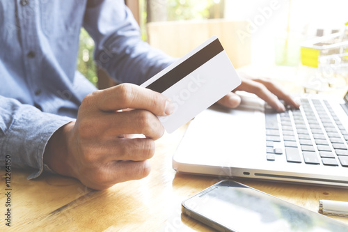Man using laptop and mobile phone to online shopping and pay by credit card. Vintage tone, Retro filter effect, Soft focus, Low light.(selective focus)