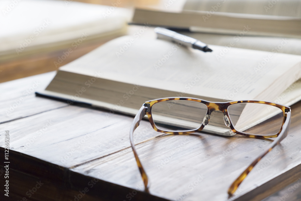 glasses on opening book in library or cafe glasses on opening book in library or cafe