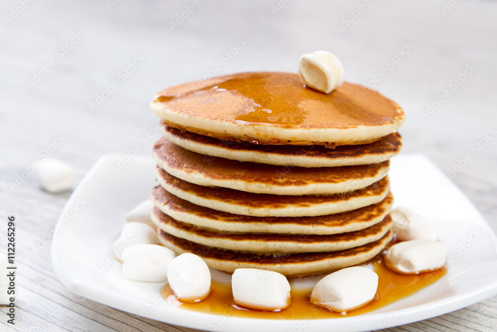 Tasty pancake on a white plate, wooden background, maple syrup Tasty pancake on a white plate, wooden background, maple syrup