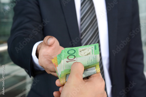 Businessman hands passing money, Australian dollar (AUD) bills