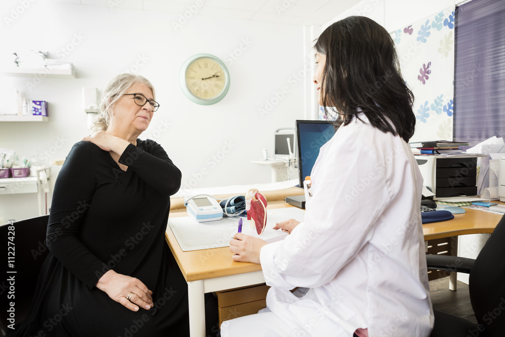 Patient Suffering From Shoulder Pain While Looking At Doctor Patient Suffering From Shoulder Pain While Looking At Doctor