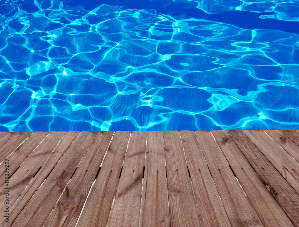 Old wooden floor and blue water in swimming pool