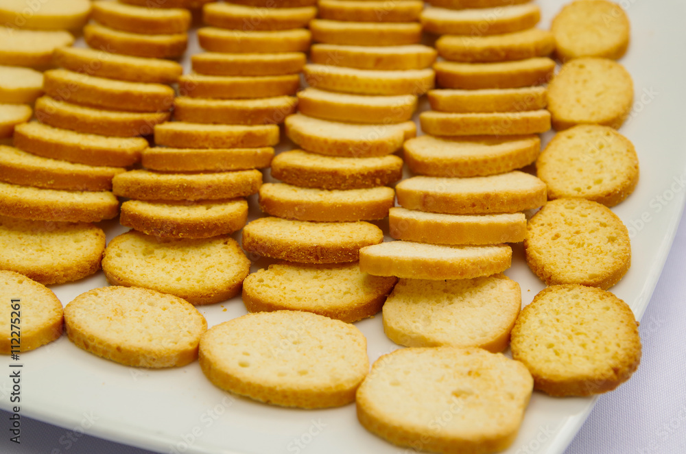 Thin crunchy toasted baguette slices stacked up on white plate Thin crunchy toasted baguette slices stacked up on white plate