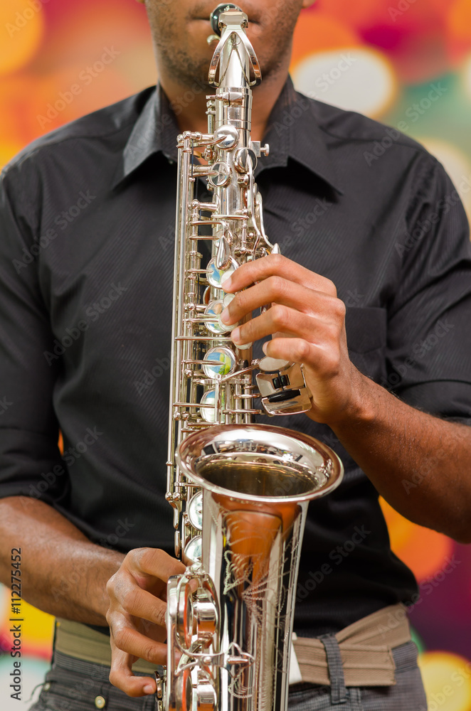 Obraz premium Closeup hands of man wearing dark shirt and playing saxophone