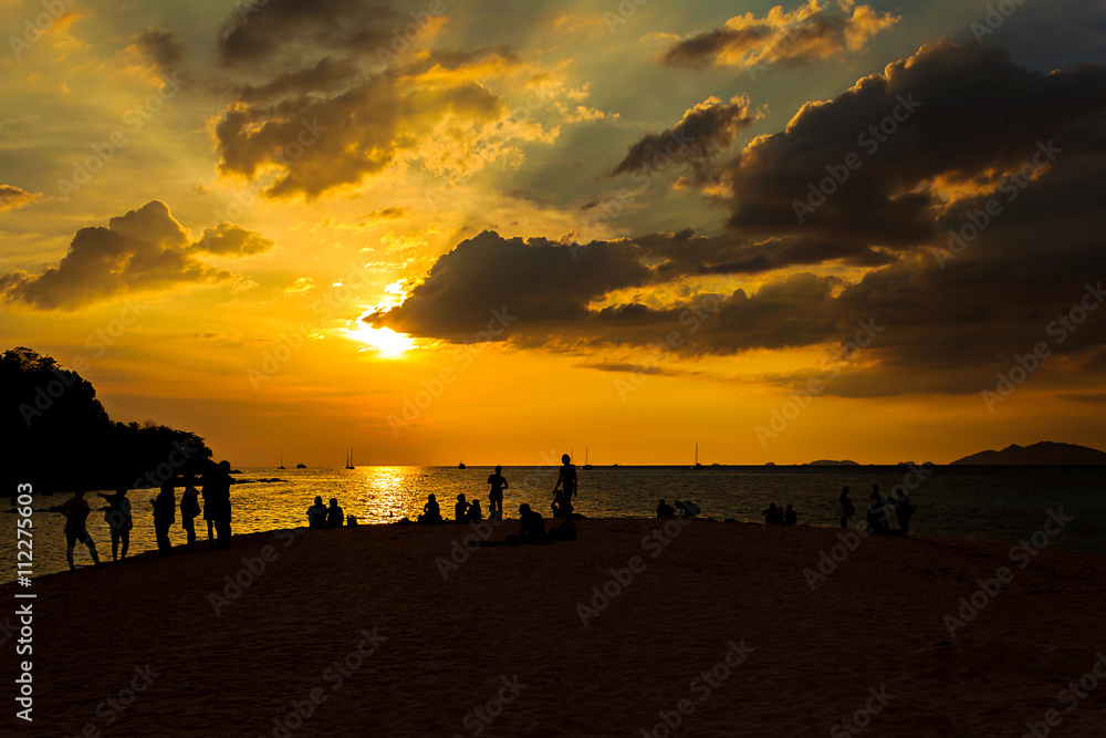 Silhouette of happy people on the beach at sunset