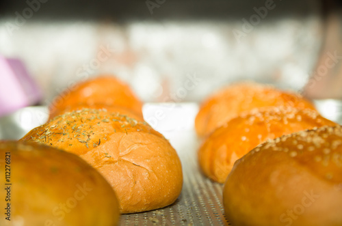 Closeup fresh baked bread buns with sesame seeds top, sitting on grey cooking surface