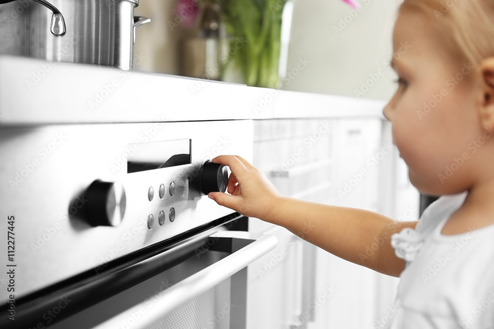 Little girl playing with electric stove in kitchen Little girl playing with electric stove in kitchen