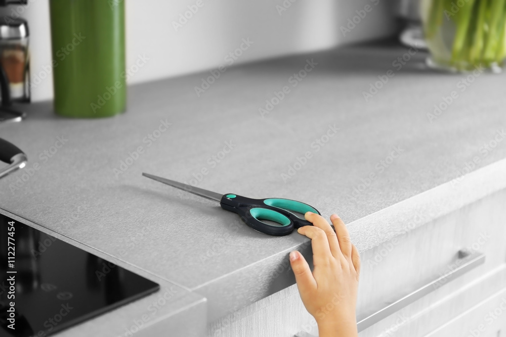 Little girl playing with scissors in kitchen