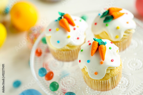 Cake stand with Easter cupcakes and eggs on wooden table