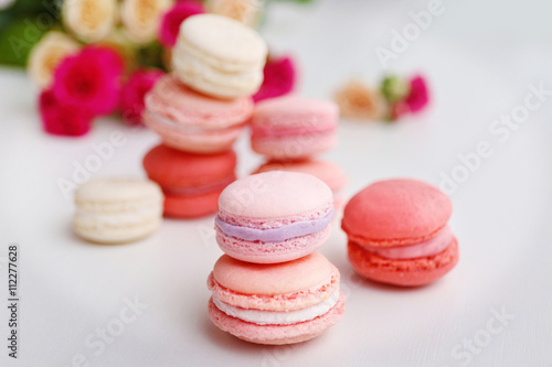 Macaroons with roses on white background