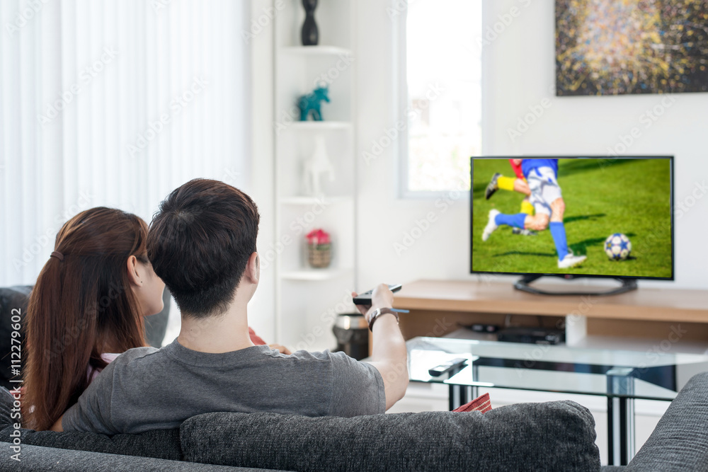 Sport, football, People concept - Young Asian couple waching foo Sport, football, People concept - Young Asian couple waching foo