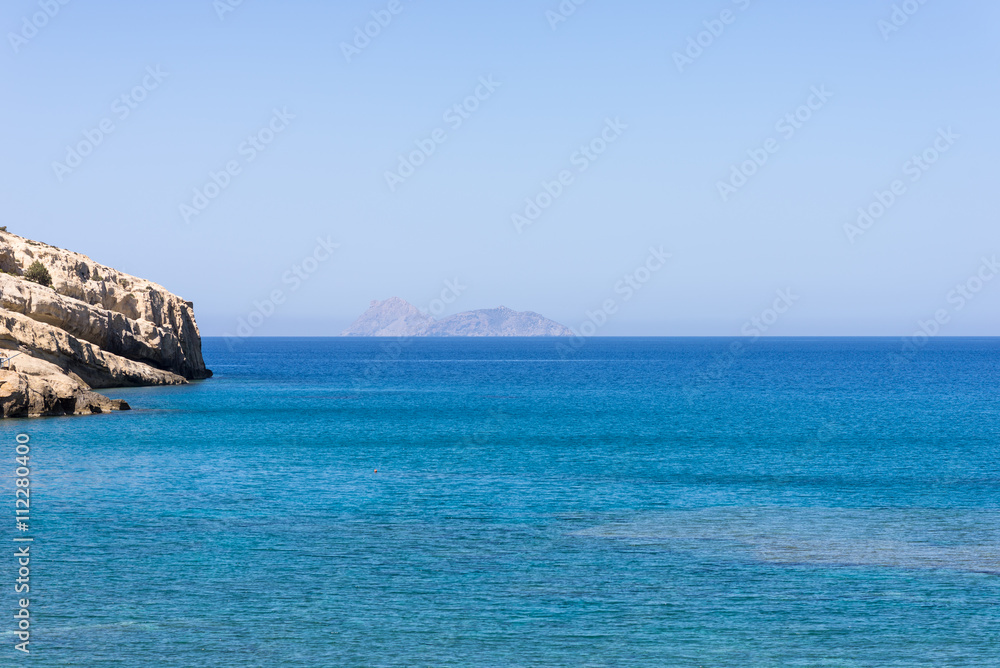 The bay of Matala in south-central Crete. In the Libyan Sea, the island Paximadia. In the foreground, the cliff of the bay. Matala is known as a hippie destination from the seventies The bay of Matala in south-central Crete. In the Libyan Sea, the island Paximadia. In the foreground, the cliff of the bay. Matala is known as a hippie destination from the seventies