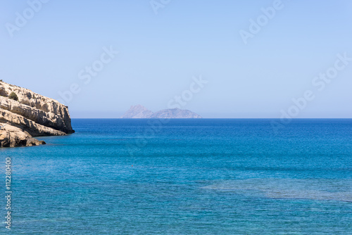 The bay of Matala in south-central Crete. In the Libyan Sea, the island Paximadia. In the foreground, the cliff of the bay. Matala is known as a hippie destination from the seventies