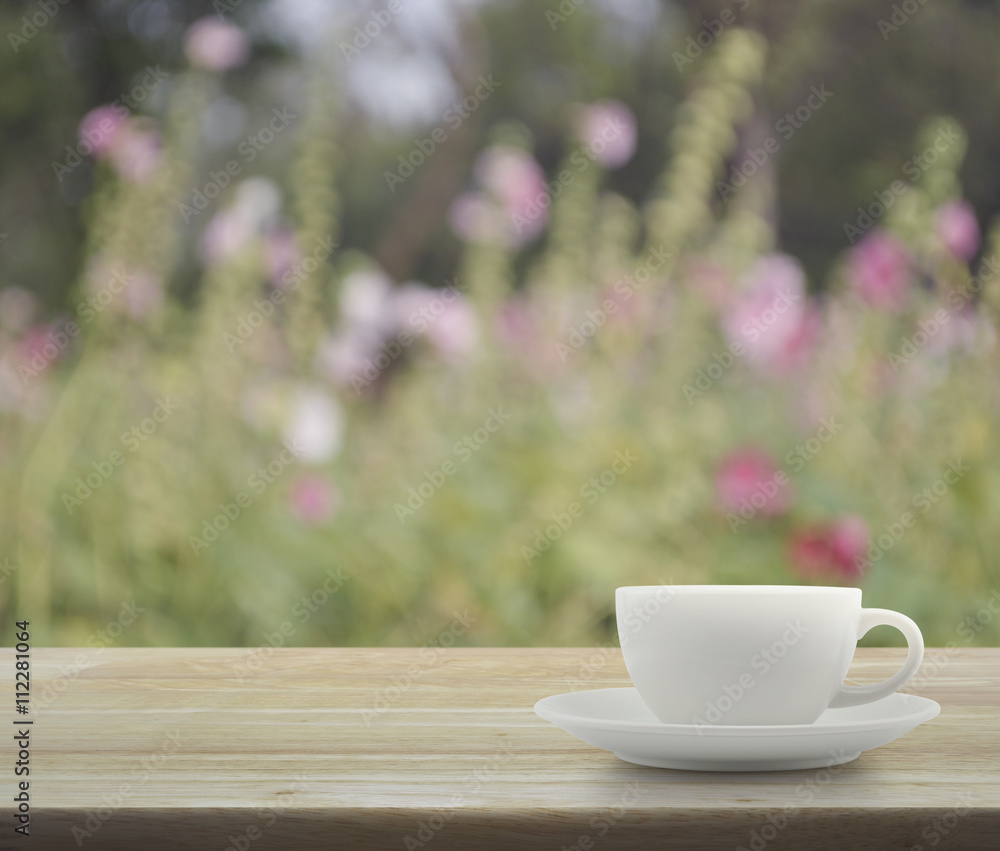 White cup on wooden table with blurred pink flower and tree, sof White cup on wooden table with blurred pink flower and tree, sof