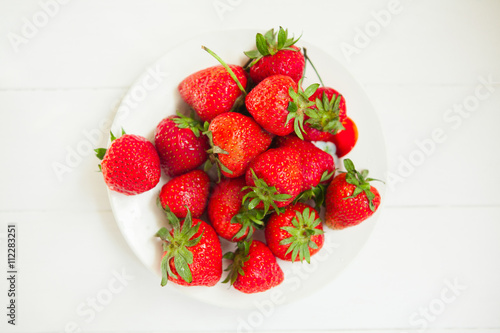 Strawberry on plate on white wooden background with copyspace. Healthy food concept. Fresh summer background.