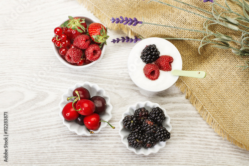 Frutos rojos, fresas, arándanos, frambuesas, guindas dentro de cuencos sobre una mesa de madera ústica. Vsta superior