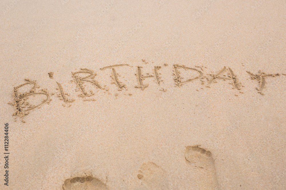 Fototapeta premium happy birthday written on the sand beach