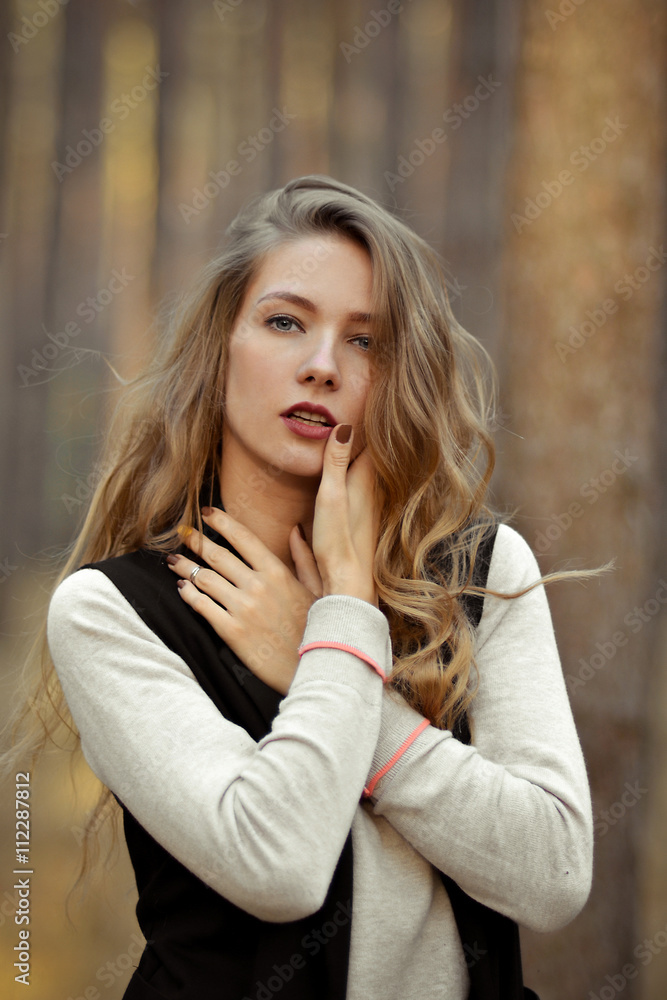 Glamorous,fashionable,sexy,sexual,seductive girl opens her mouth.Beautiful,attractive girl,model with sexual,seductive look,eyesight,red lips,long curly light hair outdoor,in summer,autumn forest,hand